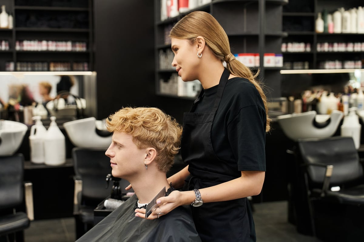 A young man sits patiently as a skilled stylist works on his new haircut in a chic salon.