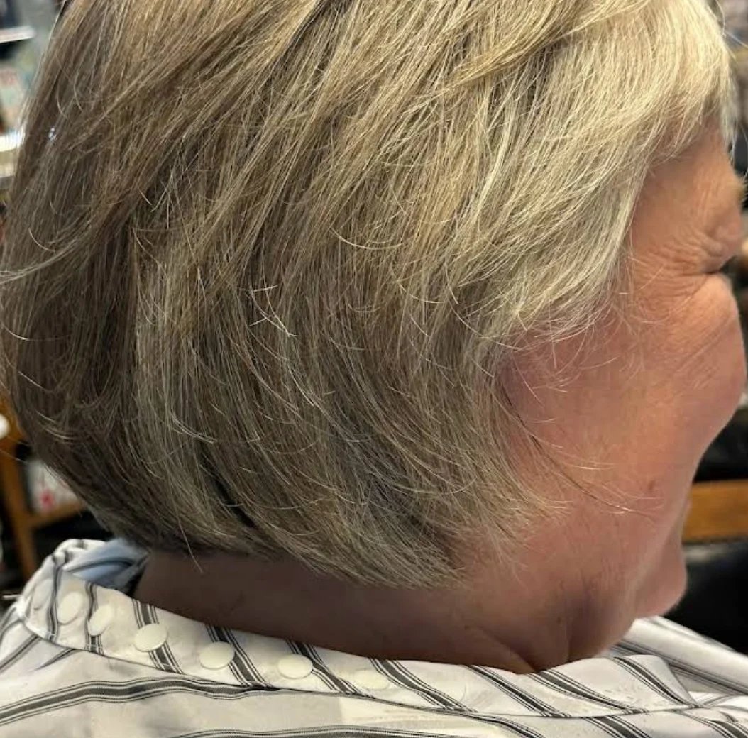 Side profile of a person with short, layered gray and blonde hair styled in a modern bob cut